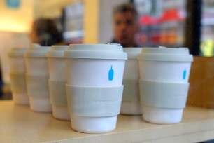 Reusable $16 takeaway ecocups are displayed for sale in the window of a Blue Bottle Coffee cafe in San Francisco.