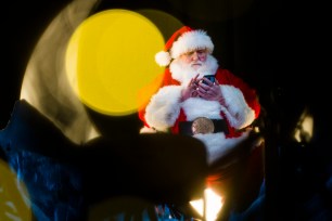 A man wearing a Santa Claus costume checks his cell phone