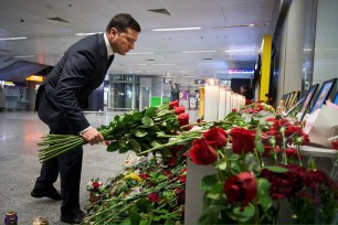 Volodymyr Zelensky lays flowers to the portraits of crew members of the Ukraine International Airlines Flight PS752 which crashed near Tehran.