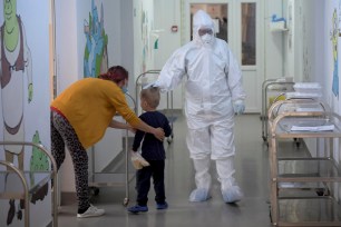 A child infected with COVID-19 is comforted by medical personnel.