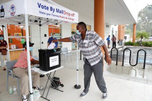 A poll worker casts a mail-in ballot for a disabled driver on the last day of early voting for the U.S. presidential election at the C. Blythe Andrews, Jr. Public Library in East Tampa, Florida.