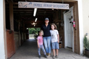 Timea Hunter poses for a photograph with her children Lena, left, and Liam, right, at the Family Horse Academy, where she is hoping to organize education for a group of children during the coronavirus pandemic.