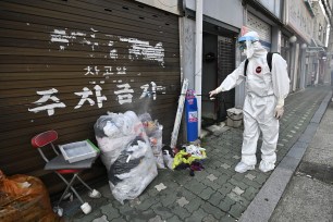 A health official wearing protective gear sprays disinfectant on the street near the Sarang Jeil Church, a new coronavirus infection cluster, in Seoul.