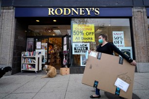 A woman carries a box while walking past a closing bookstore in Cambridge, Massachusetts, last month.