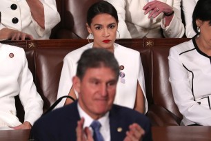 AOC remains seated during last year's State of the Union, while Joe Manchin stands to applaud.