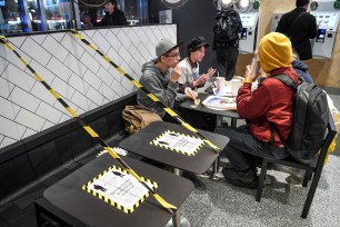 Guests eating at a fast food restaurant next to taped off tables in Stockholm today.