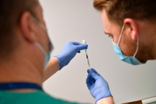 A staff member uses a needle and a vial of Pfizer-BioNTech COVID-19 vaccine