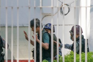 In this Feb. 26, 2021, photo, Japanese journalist Yuki Kitazumi raises his hands as he is escorted by police upon arrival at the Myaynigone police station in Sanchaung township in Yangon, Myanmar.