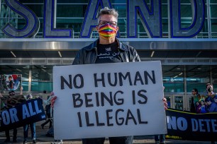 Protester seen holding a sign that says "No human being is illegal."