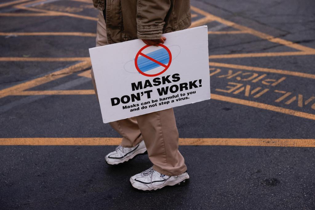 A protester holds a placard during a protest against the use of masks to prevent the spread of coronavirus disease.