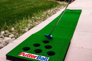 A putting green with six holes and a PutterBall logo