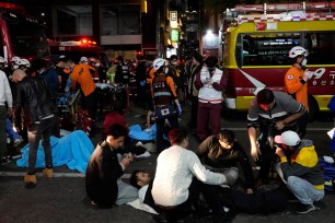 Rescue workers and firefighters try to help injured people near the scene of a crowd surge in Seoul, South Korea, Sunday, Oct. 30, 2022