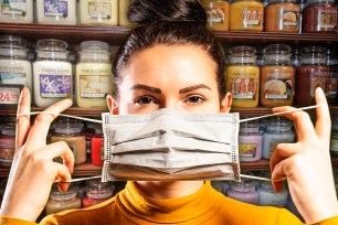 Woman with COVID mask in front of row of Yankee Candles.