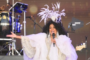 Diana Ross sings onstage with a large, white crown over her head.