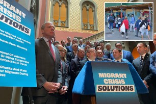 GOP Assemblymembers standing at a press conference with signs calling for action on migrant crisis with a photo of migrants in upper right corner