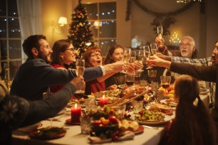 Portrait of a Handsome Young Black Man Proposing a Toast at a Christmas Dinner Table. Family and Friends Sharing Meals, Raising Glasses with Champagne, Toasting, Celebrating a Winter Holiday