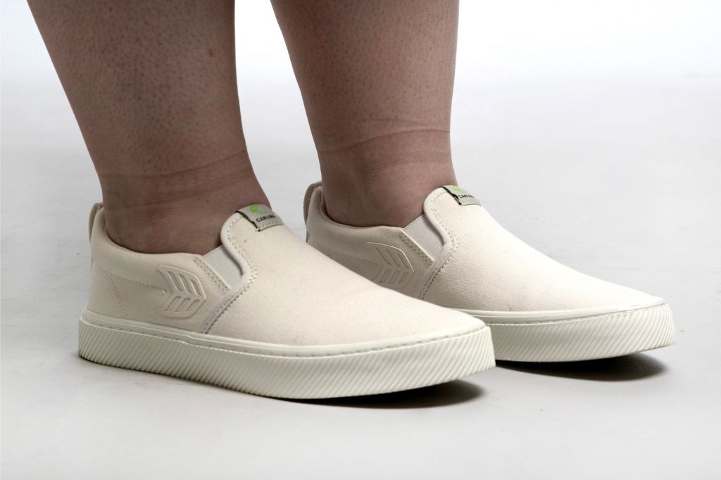 Someone wearing white slip-on walking shoes for women.