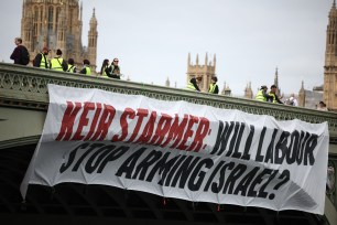 A banner reading "Keir Starmer: Will Labour Stop Arming Israel?" is hung over the side of Westminster Bridge in London on June 3, 2024, by the environmental campaign group Greenpeace.