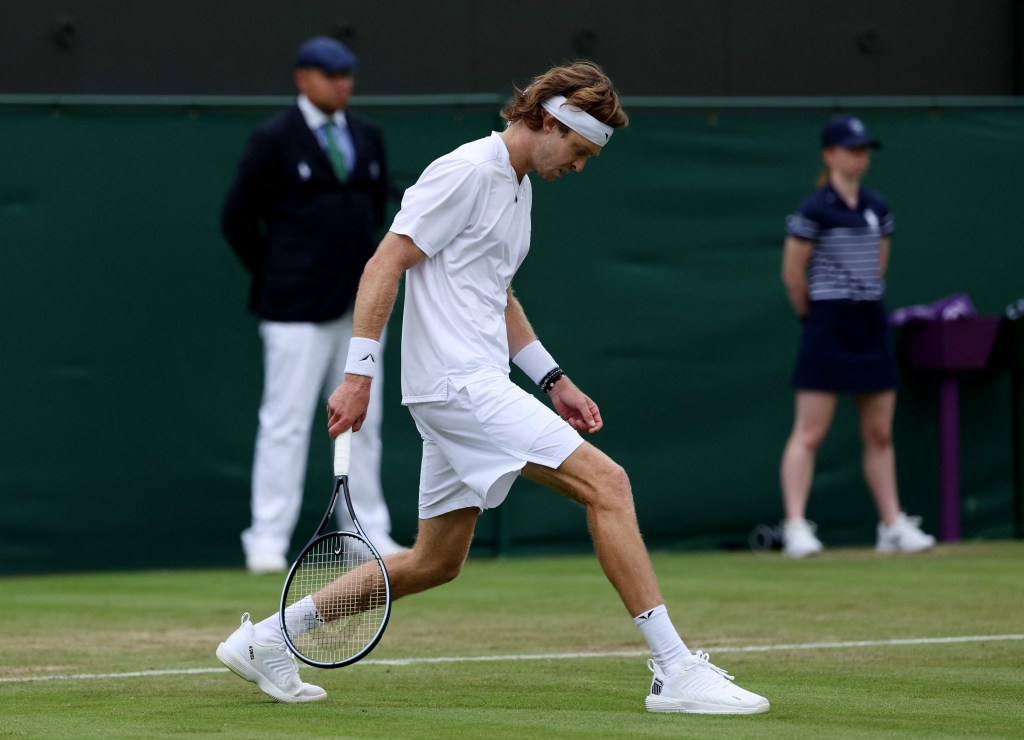 Russia's Andrey Rublev inspects the grass during his first round match against Argentina's Francisco Comesana