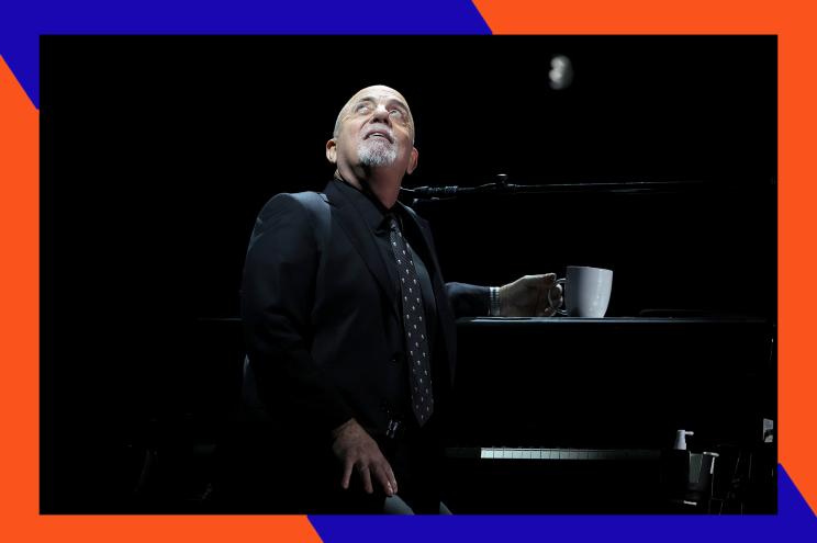 Billy Joel looks up to the rafters while sitting at his piano bench.