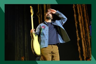 Noah Kahan salutes the crowd with a guitar in hand.