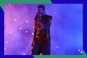 Travis Scott performs in front of ethereal purple lights.