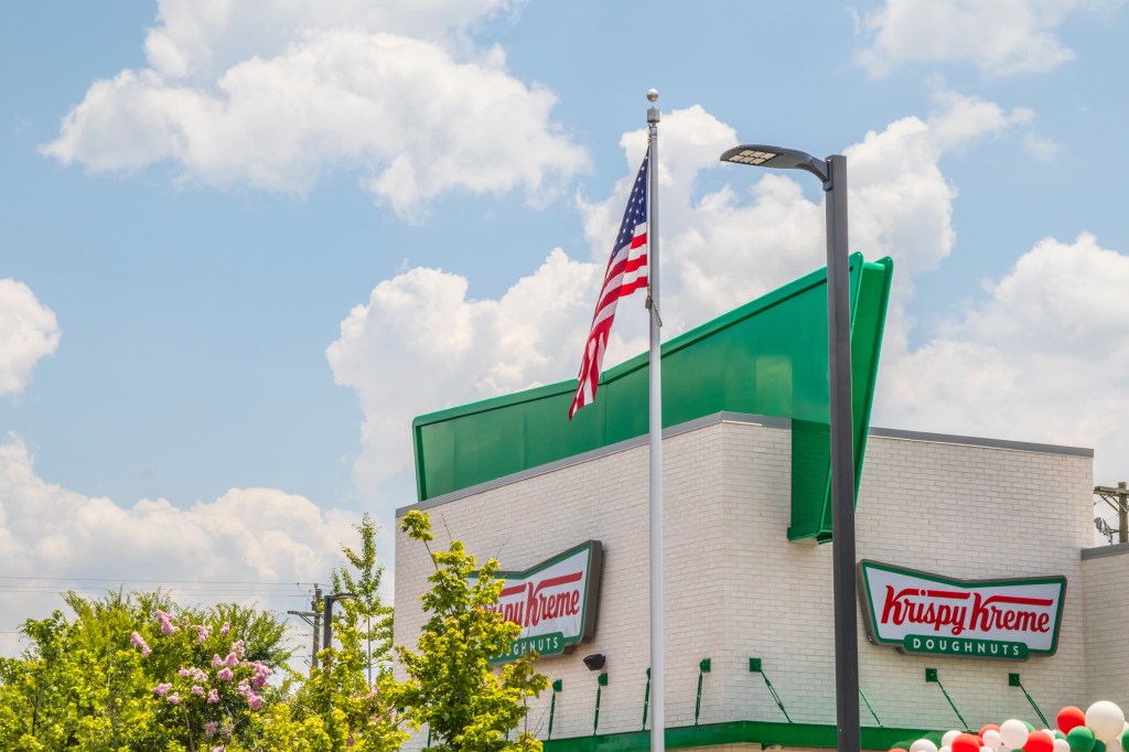 Snellville, Ga USA - 07 10 20: American flag in front of Krispy Kreme donuts Scenic Hwy; Shutterstock ID 2162963995; purchase_order: -; job: -; client: -; other: -