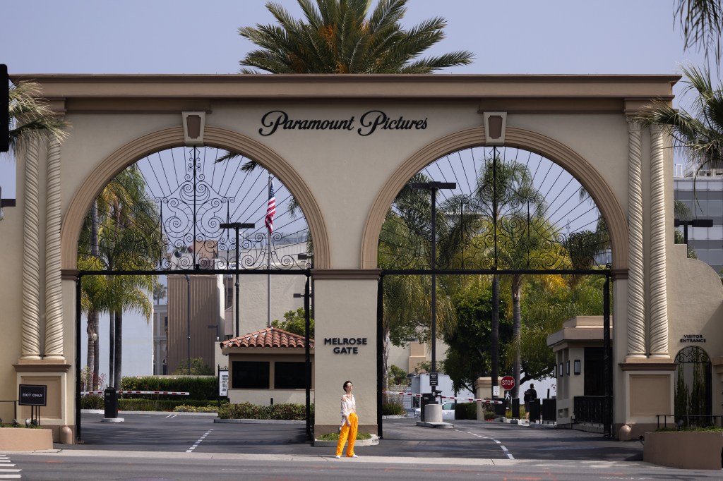 Man posing for a photo at Paramount Pictures studio lot with the studio gate in the background