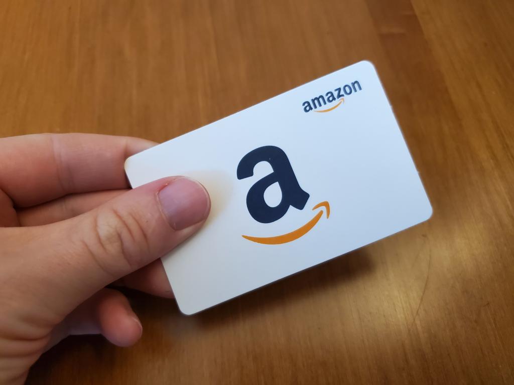 Hand holding a white Amazon gift card.