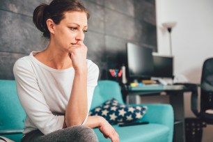 Sad woman sitting alone on a sofa in a living room