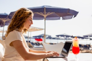 STOCK Woman using laptop to check email for work and using laptop computer on beach.