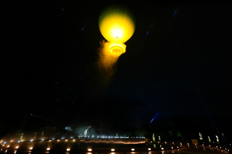 Teddy Riner and Marie-Jose Perec watch as the cauldron rises in a balloon.