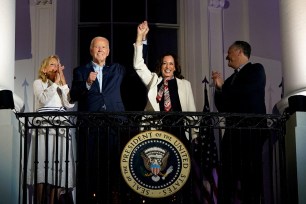 President Joe Biden and Vice President Kamala Harris raise their hands as they stand on a White House balcony