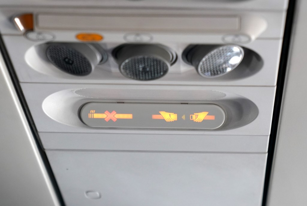 A general view of a seat belt light and a no smoking light on a commercial airplane.