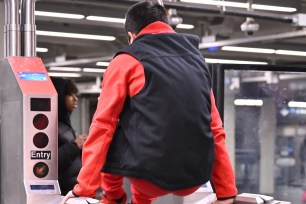 A man jumping over a subway turnstile at the Times Square 42nd Street and Broadway station.