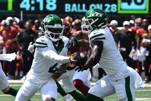 Jets quarterback Tyrod Taylor (2) hands off the ball to running back Braelon Allen, right, during the first quarter on August 10, 2024.