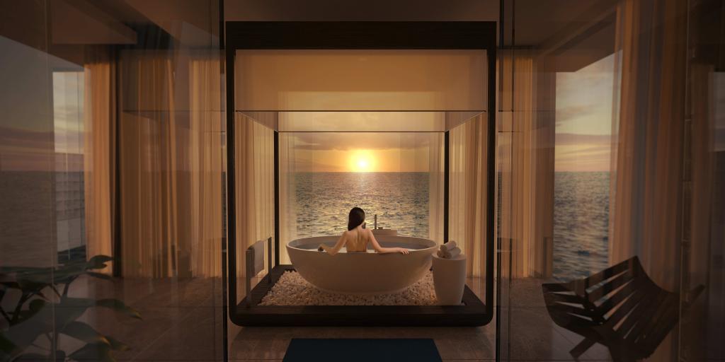 A woman relaxing in a bathtub in the Muraka suite at Conrad Maldives Rangali Island, with a scenic ocean view