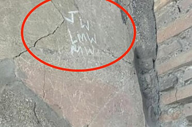 A stone wall adorned with red circles and white text