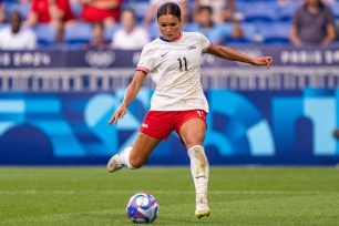 A woman in a football uniform kicking a ball