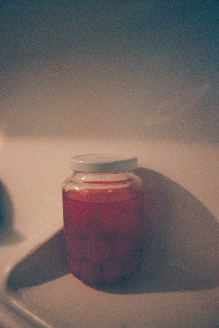 A jar of Maraschino cherries in the door of a refrigerator.