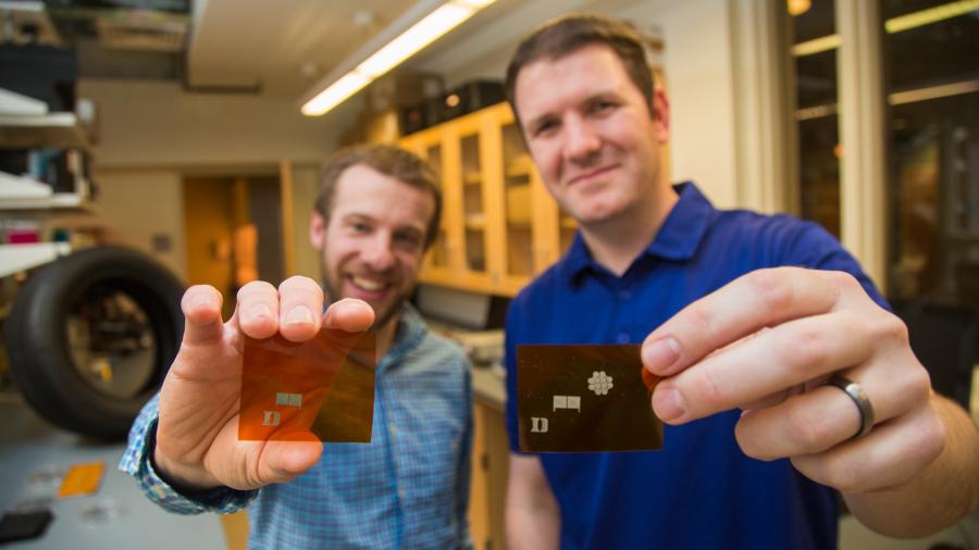 two people hold cards of printed electronics at Duke University