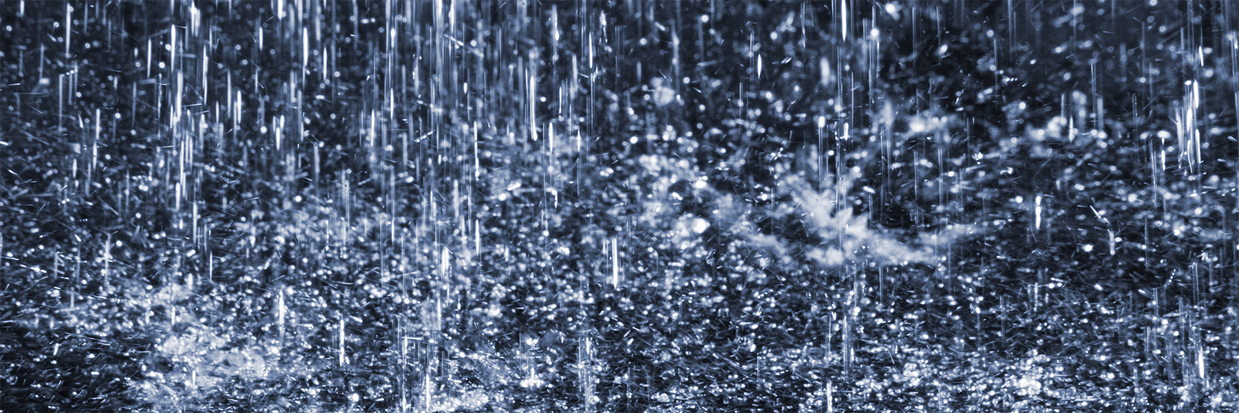 Heavy rain falls on a dark background. Credit: Adobe Stock