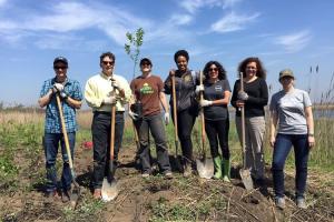 Group of people digging in dirt holding shovels.
