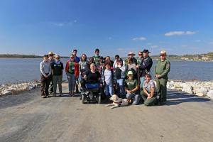 Group of people posing for a photo in front of water.