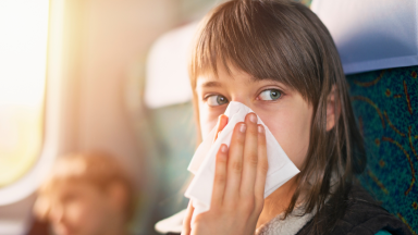 Teenage girl blowing nose on a plane