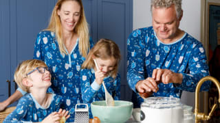 A family wearing matching Hanukkah pajamas making potato pancakes in a kitchen