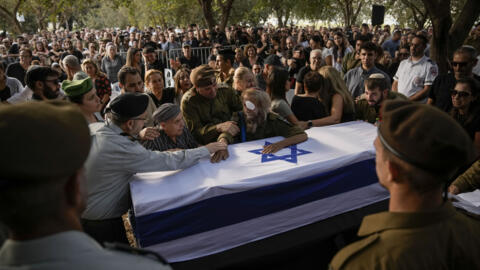 People touch the flagged-covered coffin of Israeli soldier Sgt. Amitai Alon, killed by a Hezbollah drone attack, during his funeral near Ramot Naftali, Israel on Monday, October 14, 2024.