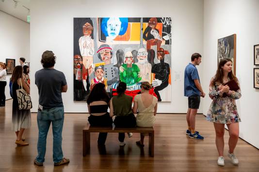 Several museum visitors viewing artworks in a gallery.