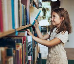 girl picking book off shelf