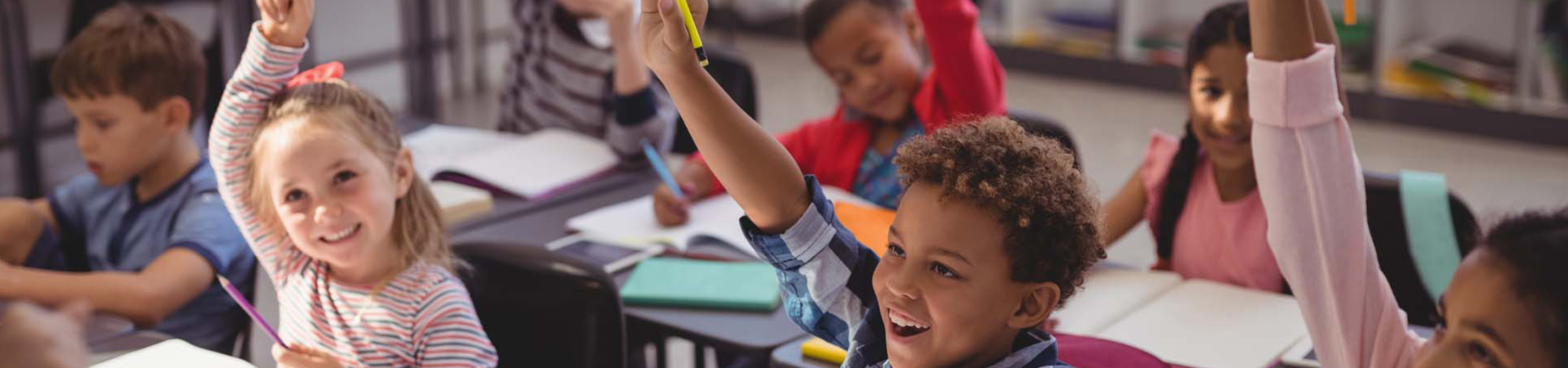 kids in classroom raising hands